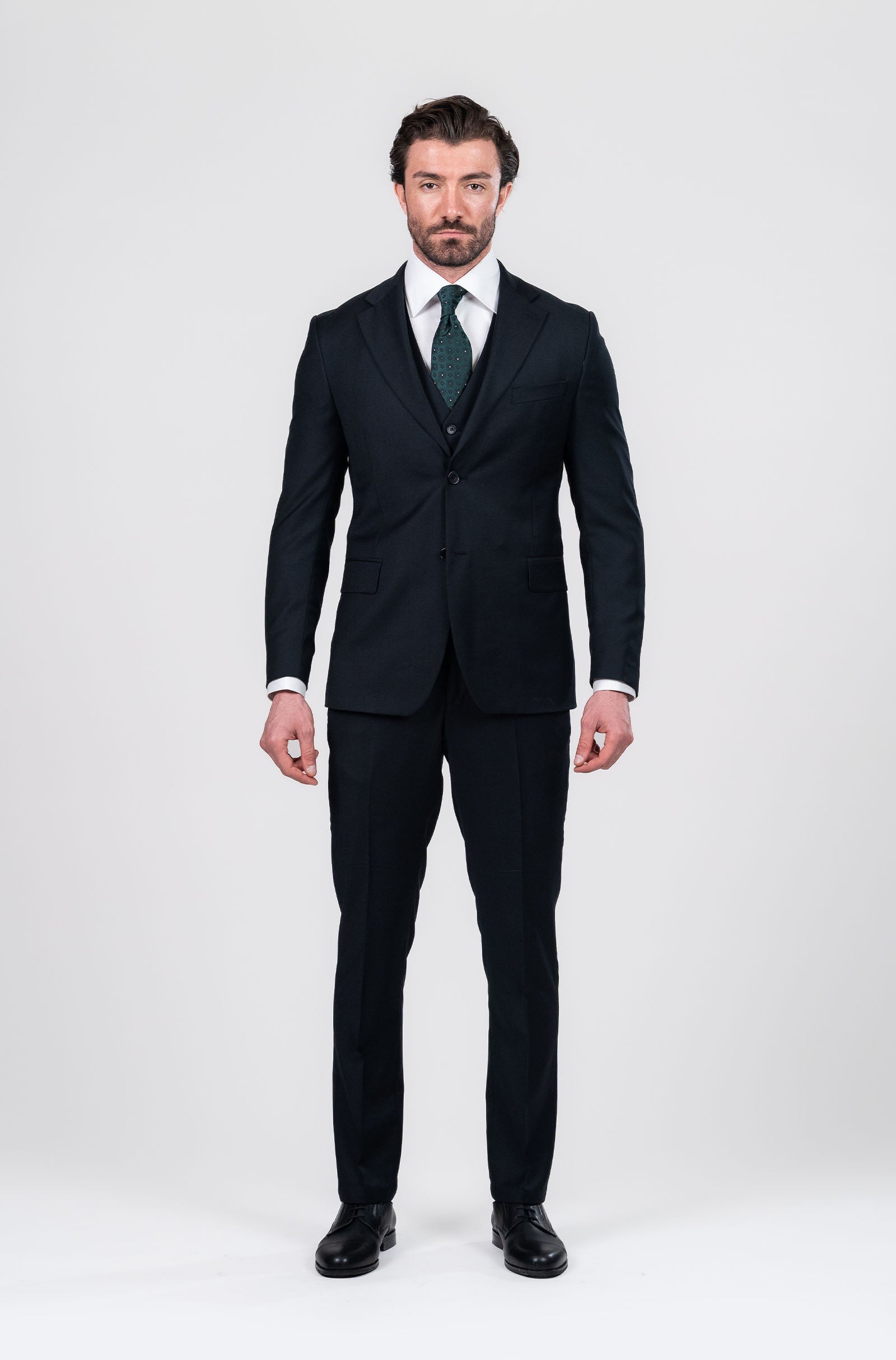 Man wearing a black suit with a green tie on a white background