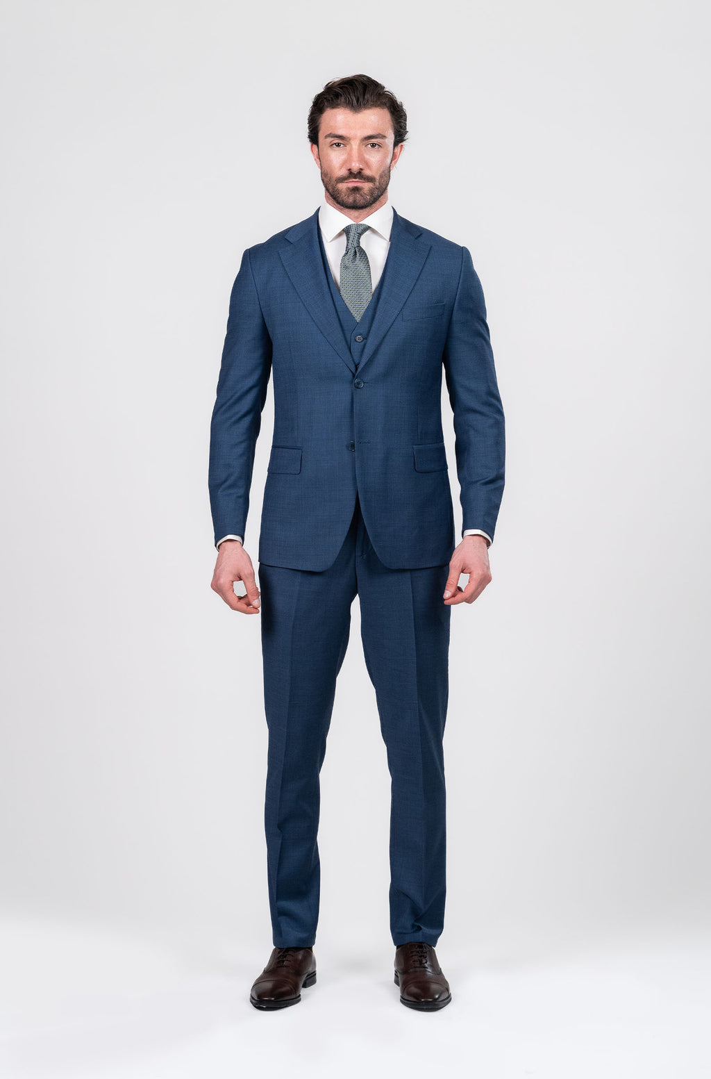 Man wearing a blue suit with a white shirt and tie on a white background